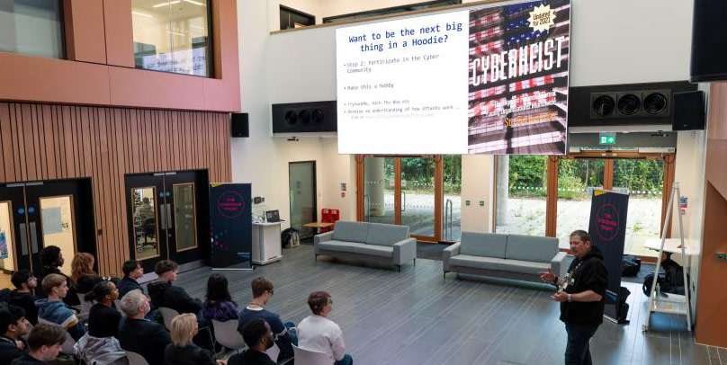 A presenter speaking to a crowd at the Cyber, Safety & Security Roadshow event