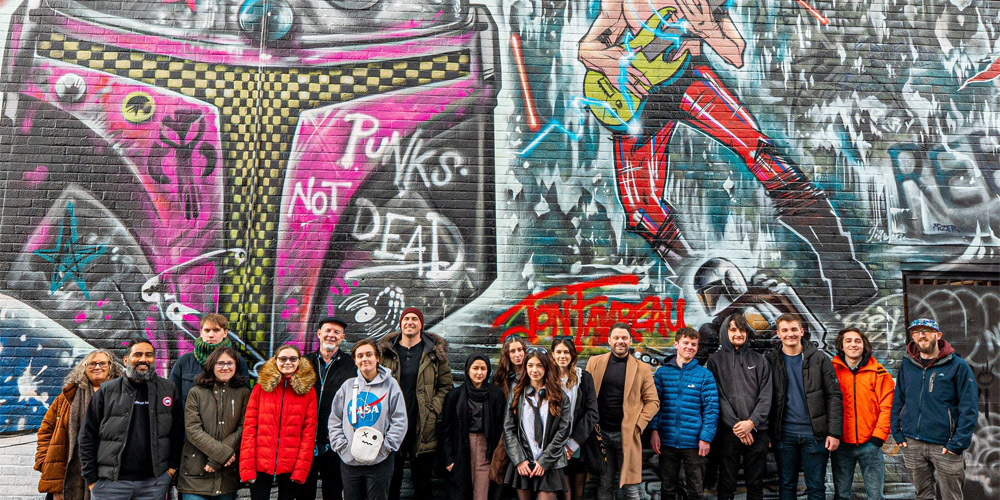 Students who took part in The CyberHub Trust creative challenge standing in front of a graffitied wall