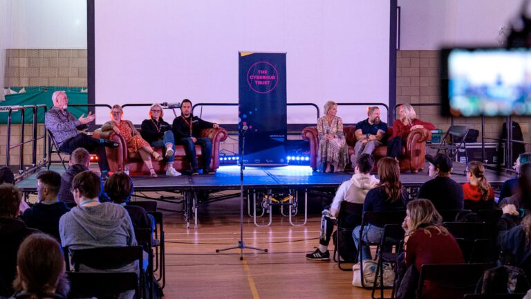 Guest speakers sitting on couches on stage at the Film And Gaming Event